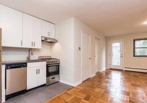 Kitchen with sleek wood tile flooring, white cabinetry, and stainless steel appliances.